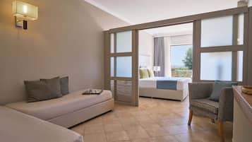 A modern hotel room with a sofa, a chair, a bed, and a balcony with a view.