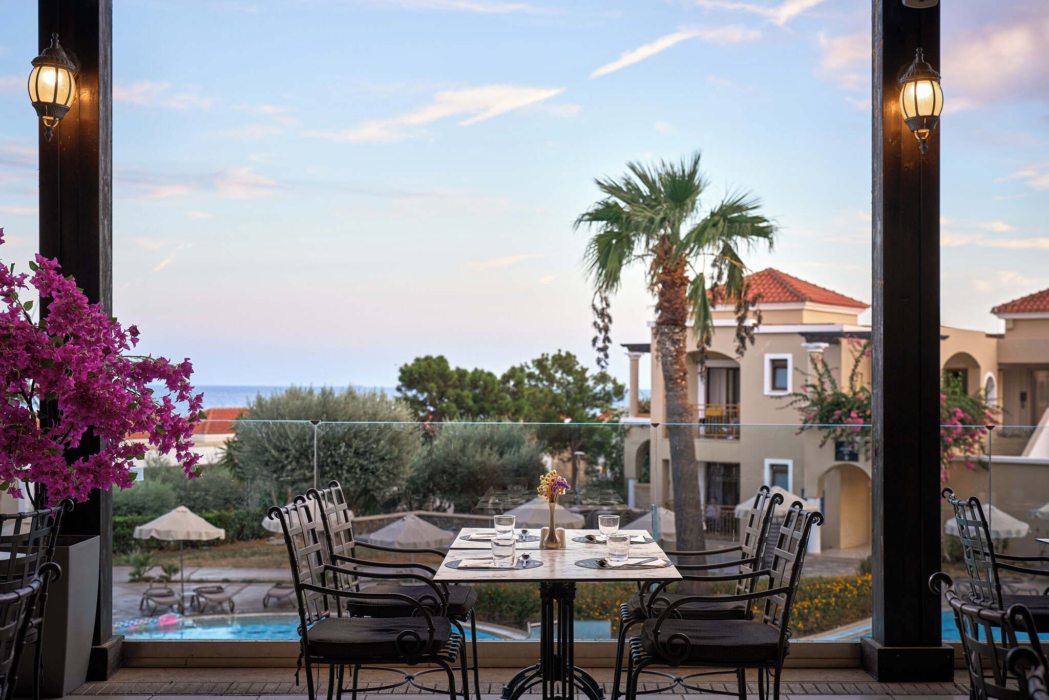 Ein Essbereich mit einem Tisch für zwei Personen, mit Blick auf einen Pool und das Meer.