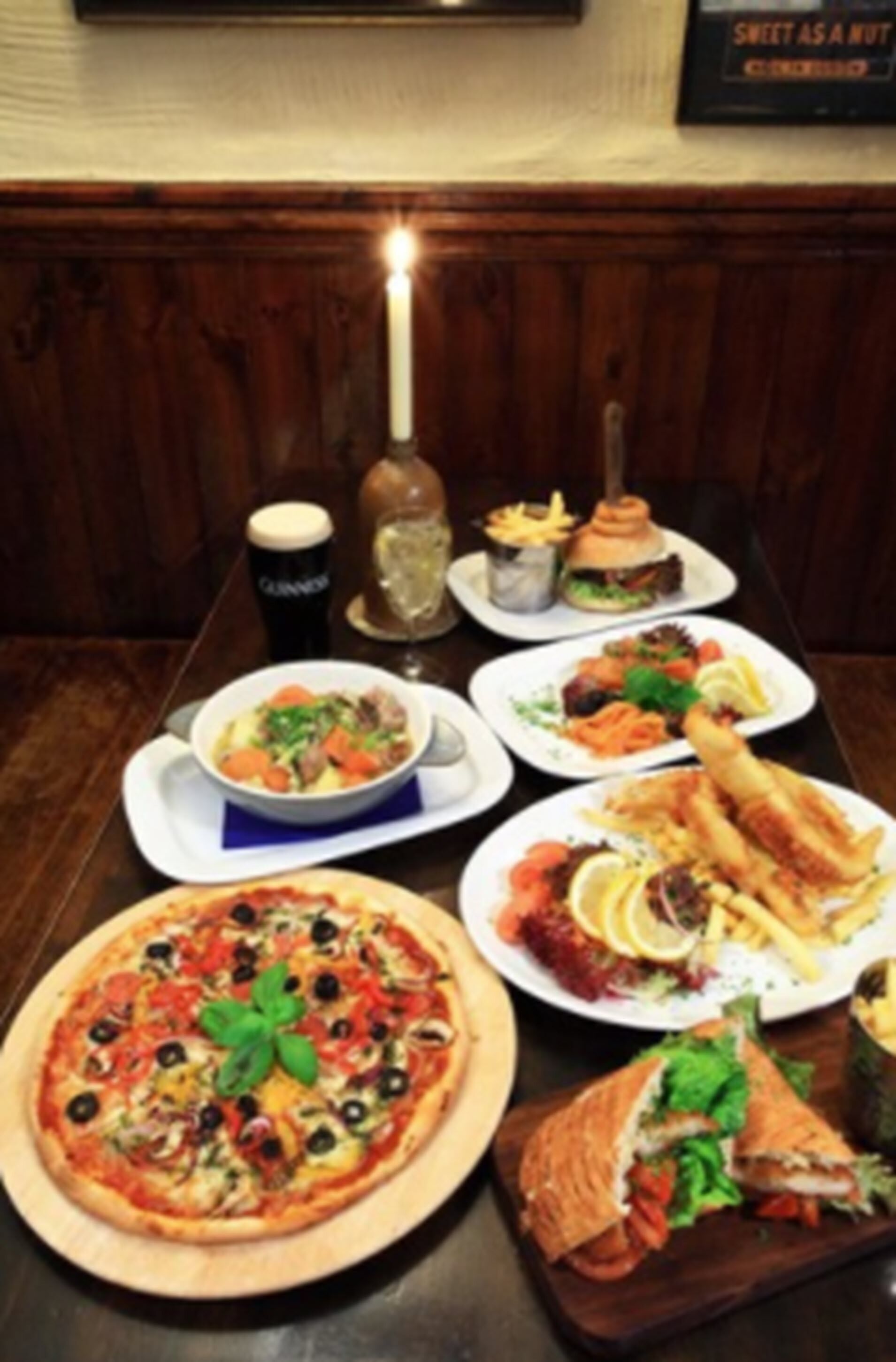 A dining table with various dishes including pizza, a sandwich, and a salad.