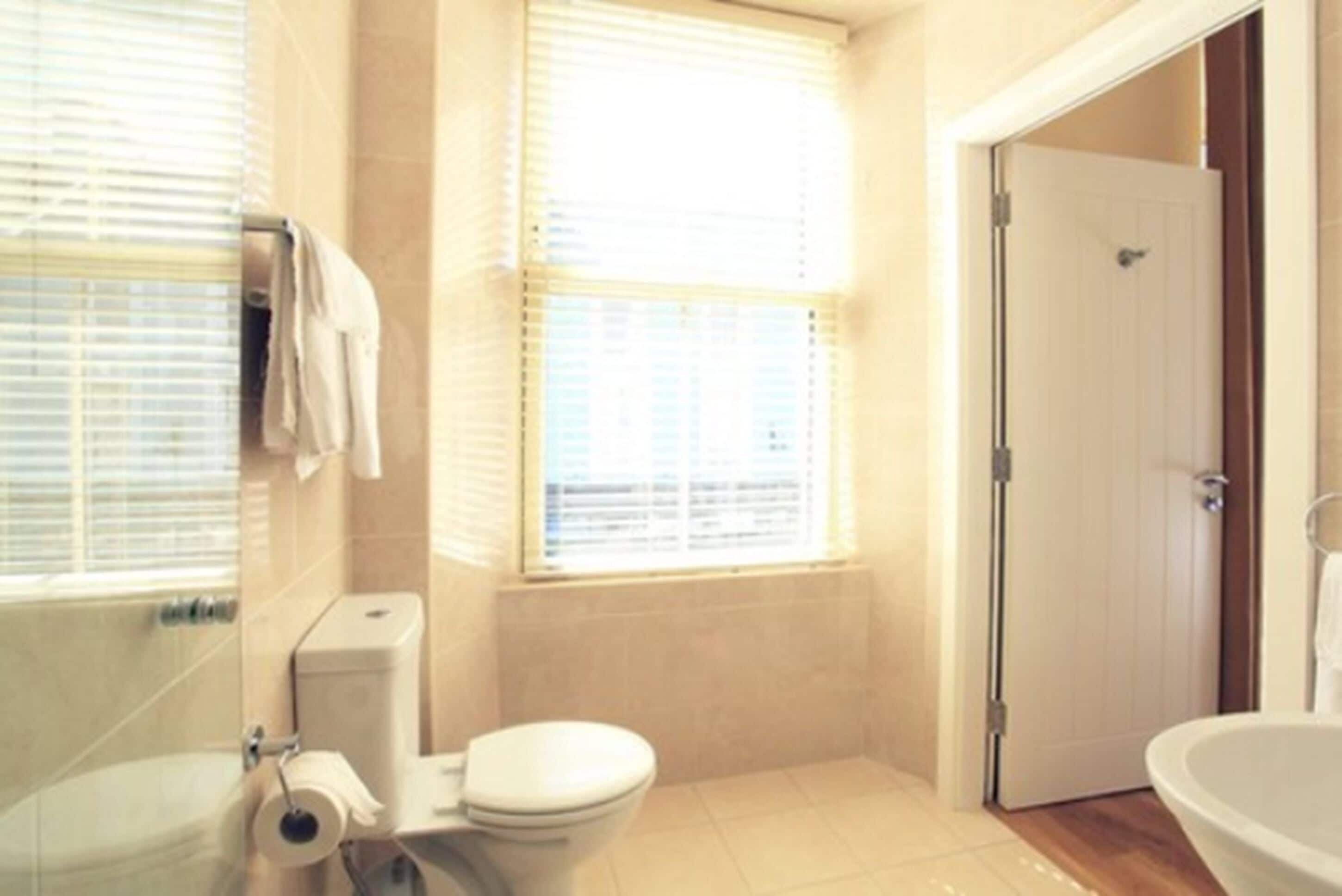 A bathroom with a toilet, a sink, and a window with blinds.