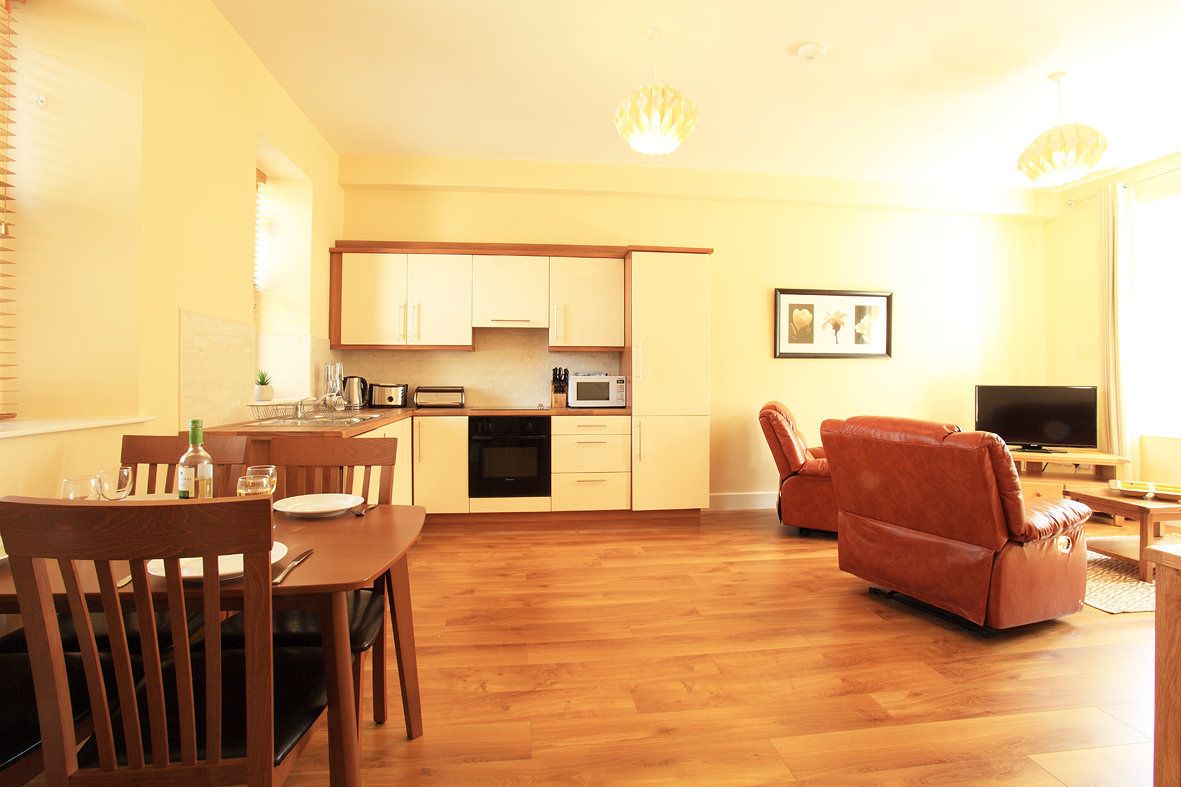 A compact living space with a dining area, kitchenette, and a seating area with a television.