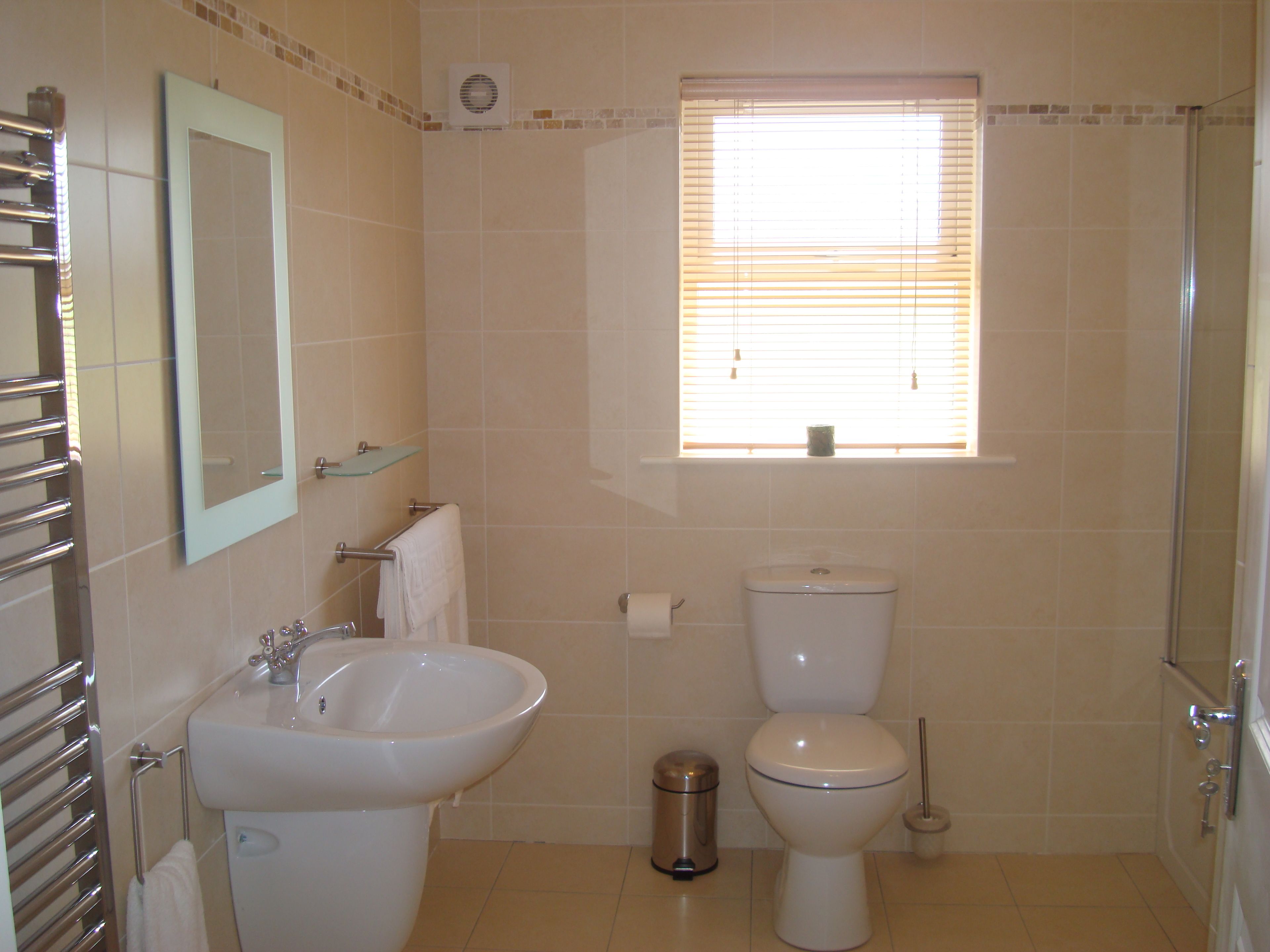 Een badkamer met een wastafel, toilet en een raam met zonwering.