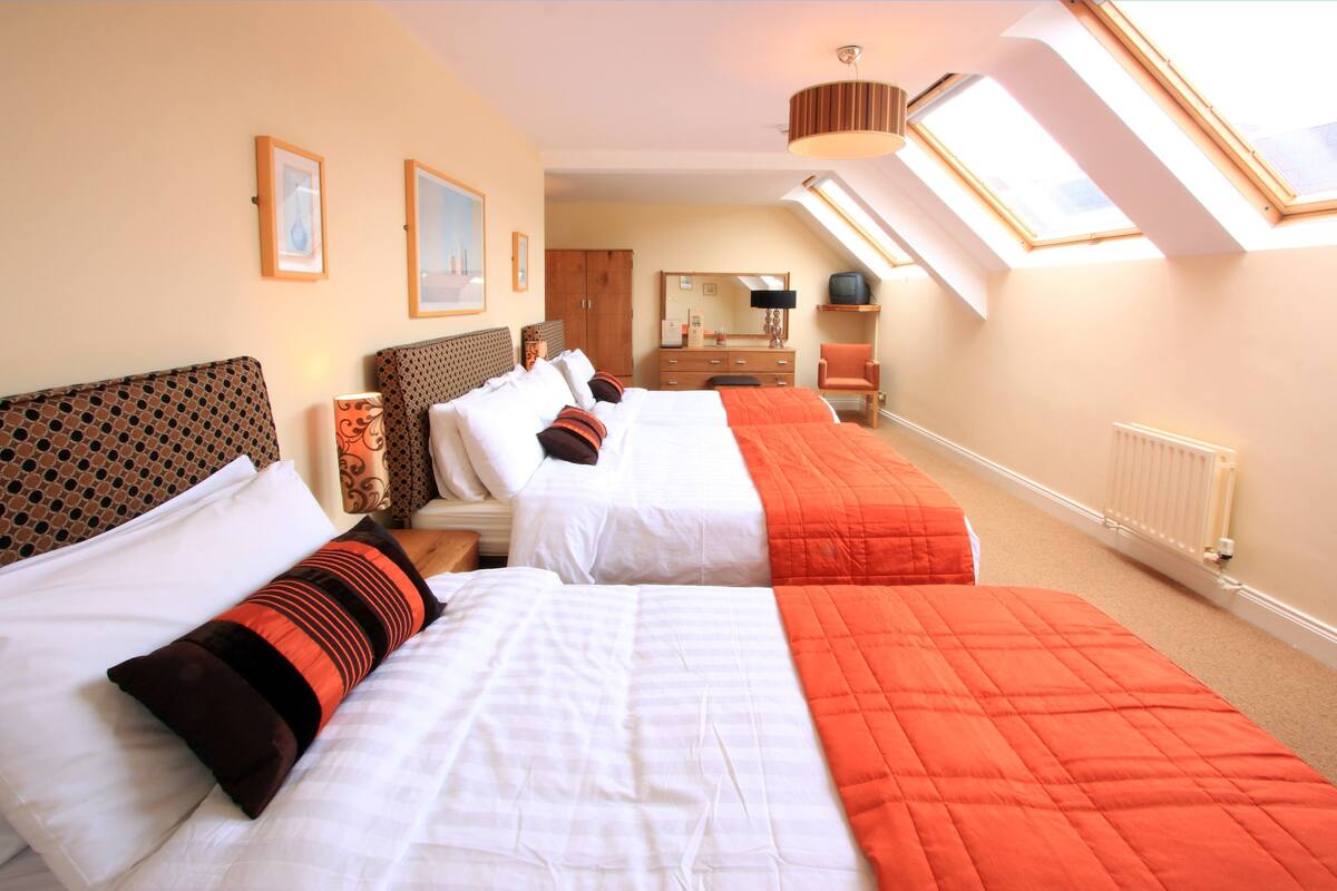 Een hotelkamer met twee bedden, een kaptafel, een stoel, een spiegel en dakramen.