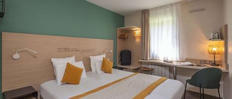 Una habitación de hotel con una cama, un escritorio, una silla y una ventana con cortinas.