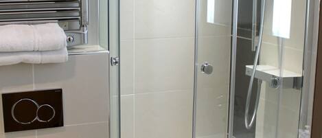 A modern bathroom with a glass-enclosed shower, a toilet, and a towel rack.