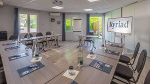 Un salón de conferencias con proyector, pantalla de presentación y mesas con botellas de agua y blocs de notas.