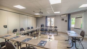 Un salón de conferencias con una larga mesa, sillas, un proyector y una pizarra.