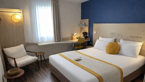 Habitación de hotel con cama, una silla, un escritorio y una ventana con cortinas.