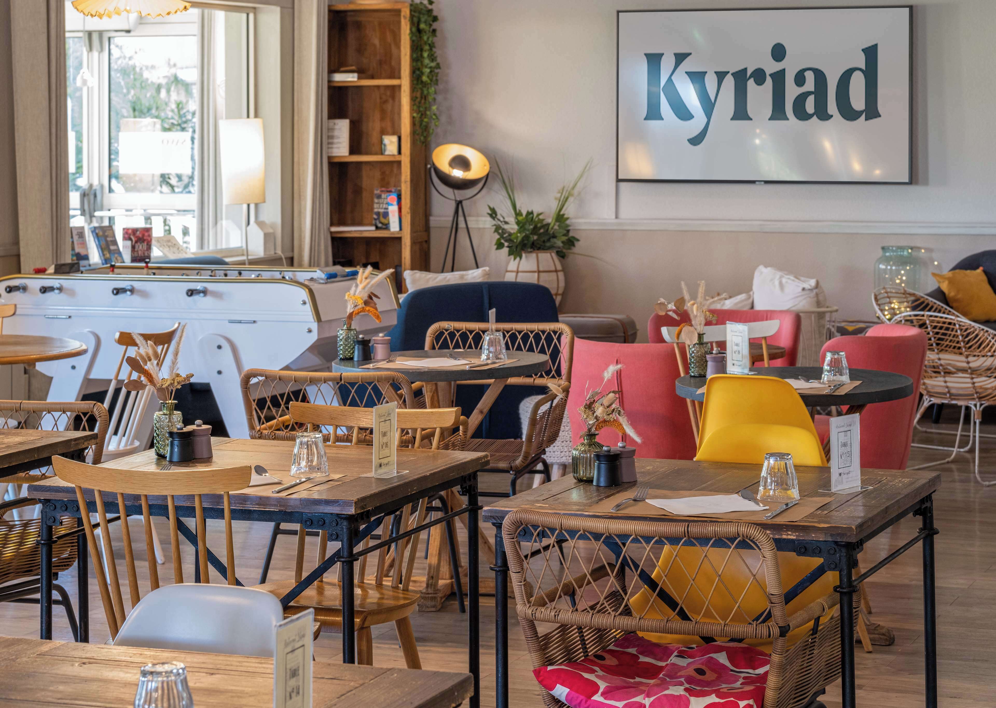 Interior acogedor de restaurante con mesas y sillas de madera, una mesa de billar y una estantería.