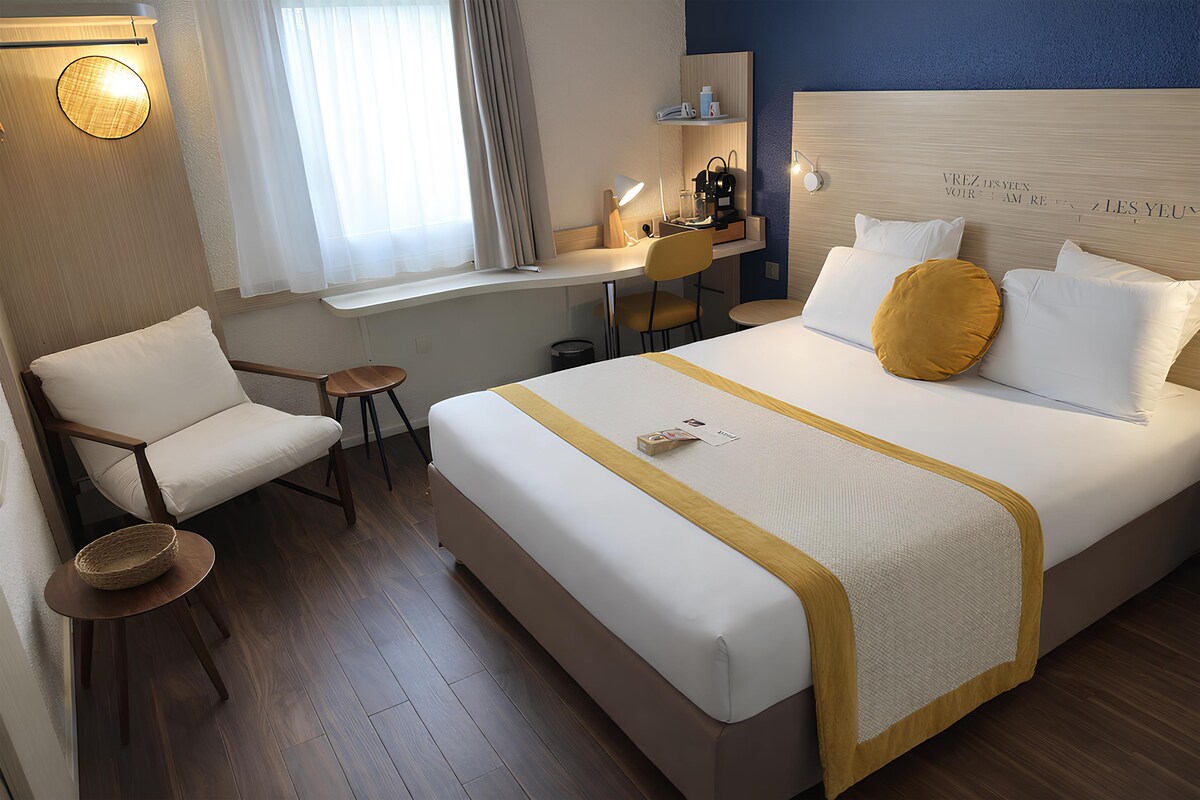 Ein Hotelzimmer mit Bett, Schreibtisch, Stuhl und einem kleinen Tisch.