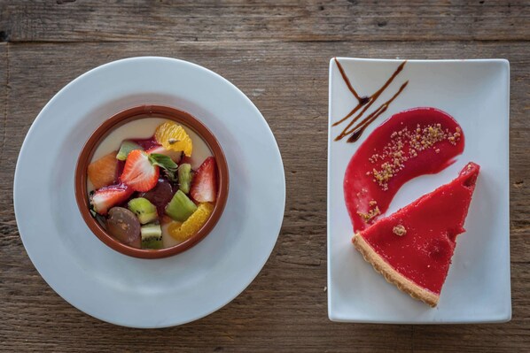 A dessert plate with a red tart and a bowl of fruit salad.