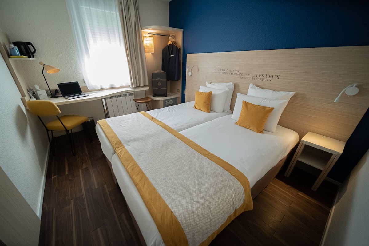 Une chambre d’hôtel comprenant un lit, un bureau avec un ordinateur portable, une chaise et une armoire.