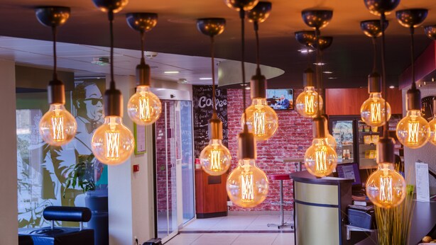 A modern interior with hanging light fixtures and a brick wall. - ibis Styles Toulouse Blagnac Aeroport (Blagnac)