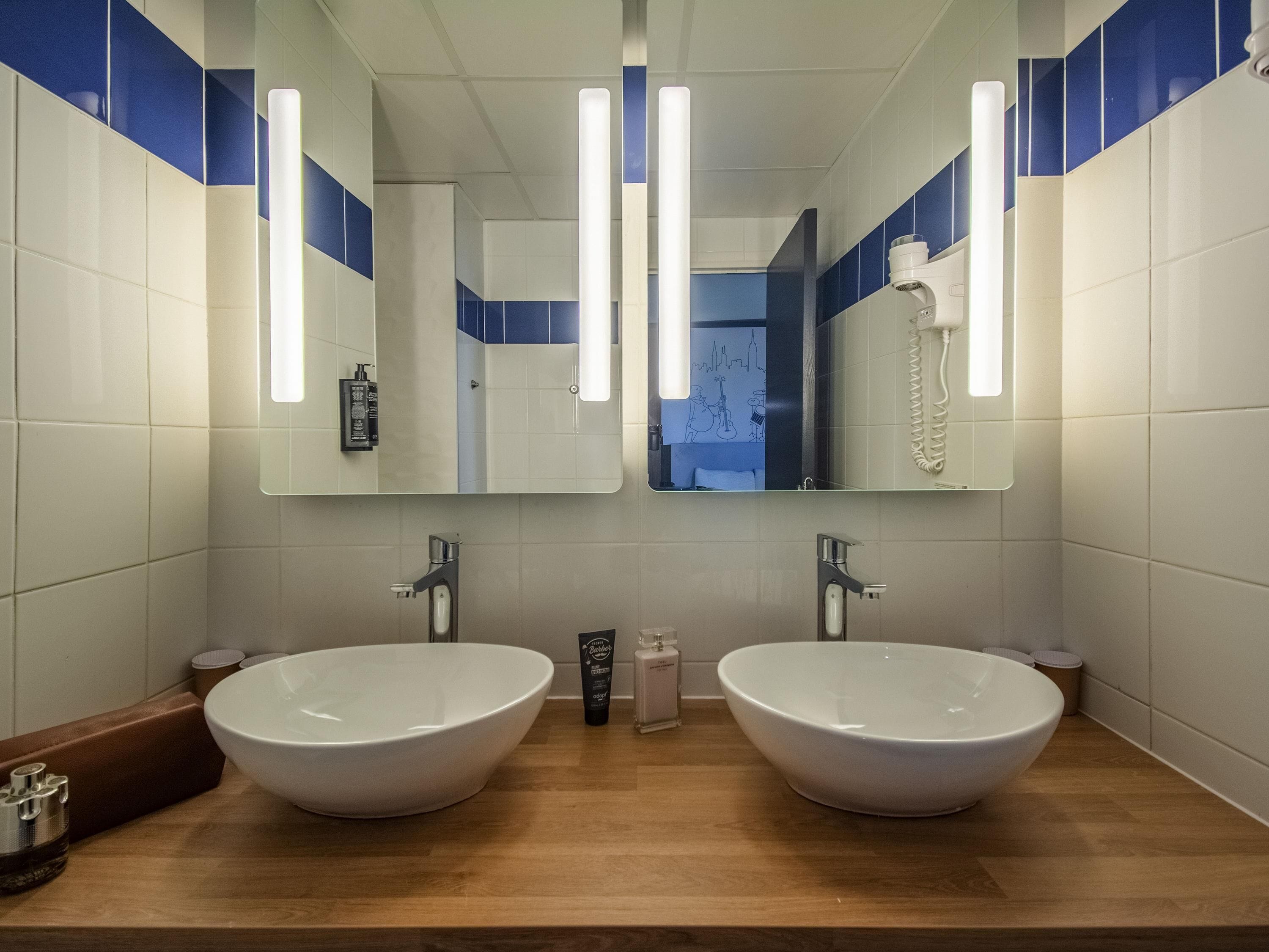 A bathroom with two sinks, a mirror, and a towel rack.