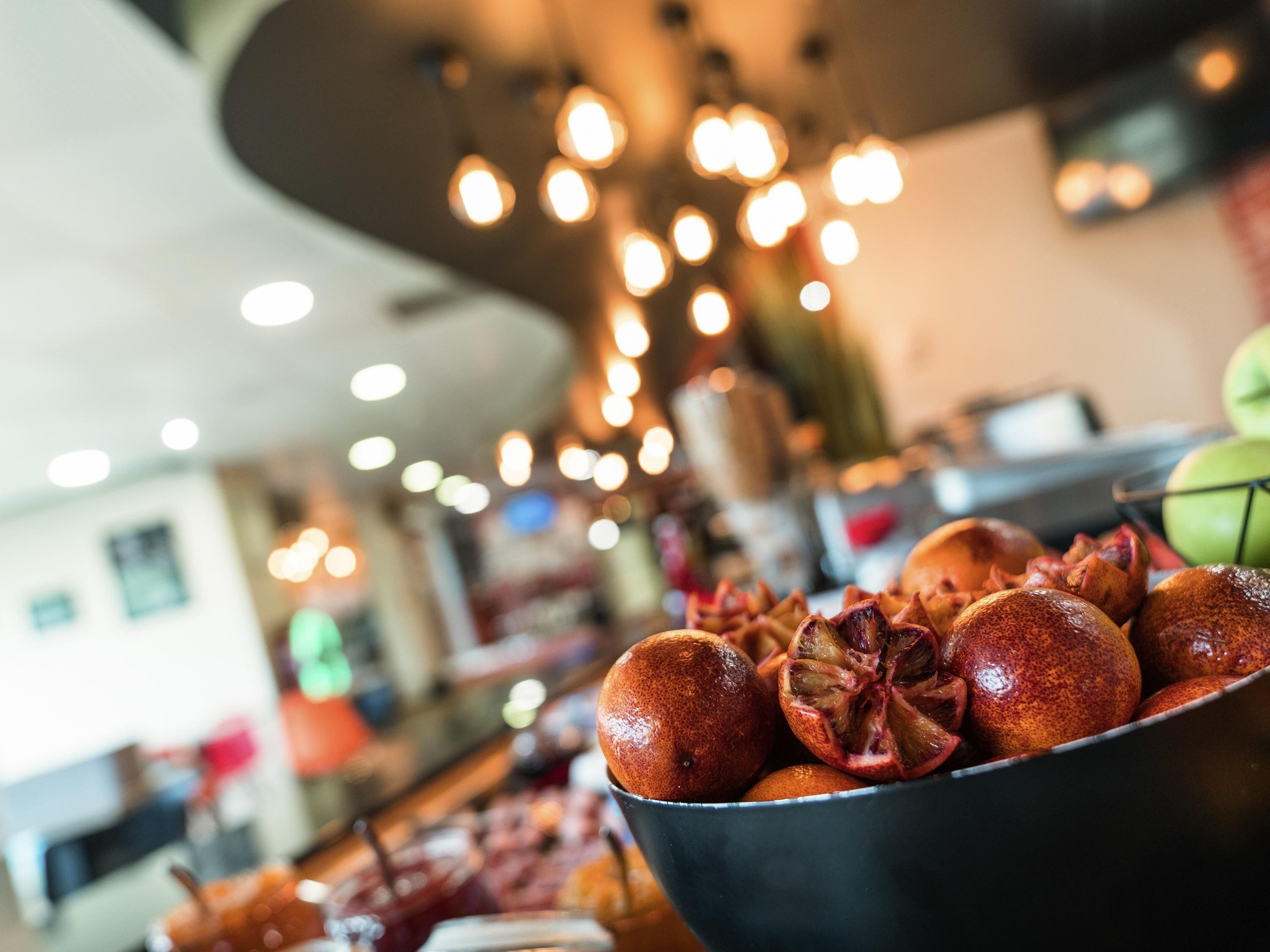 A bowl of pomegranates with a blurred background of a restaurant interior.