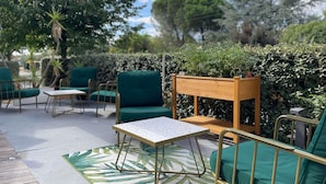 An outdoor seating area with green chairs and a table, surrounded by lush greenery and a wooden planter. - ibis Styles Toulouse Blagnac Aeroport (Blagnac)