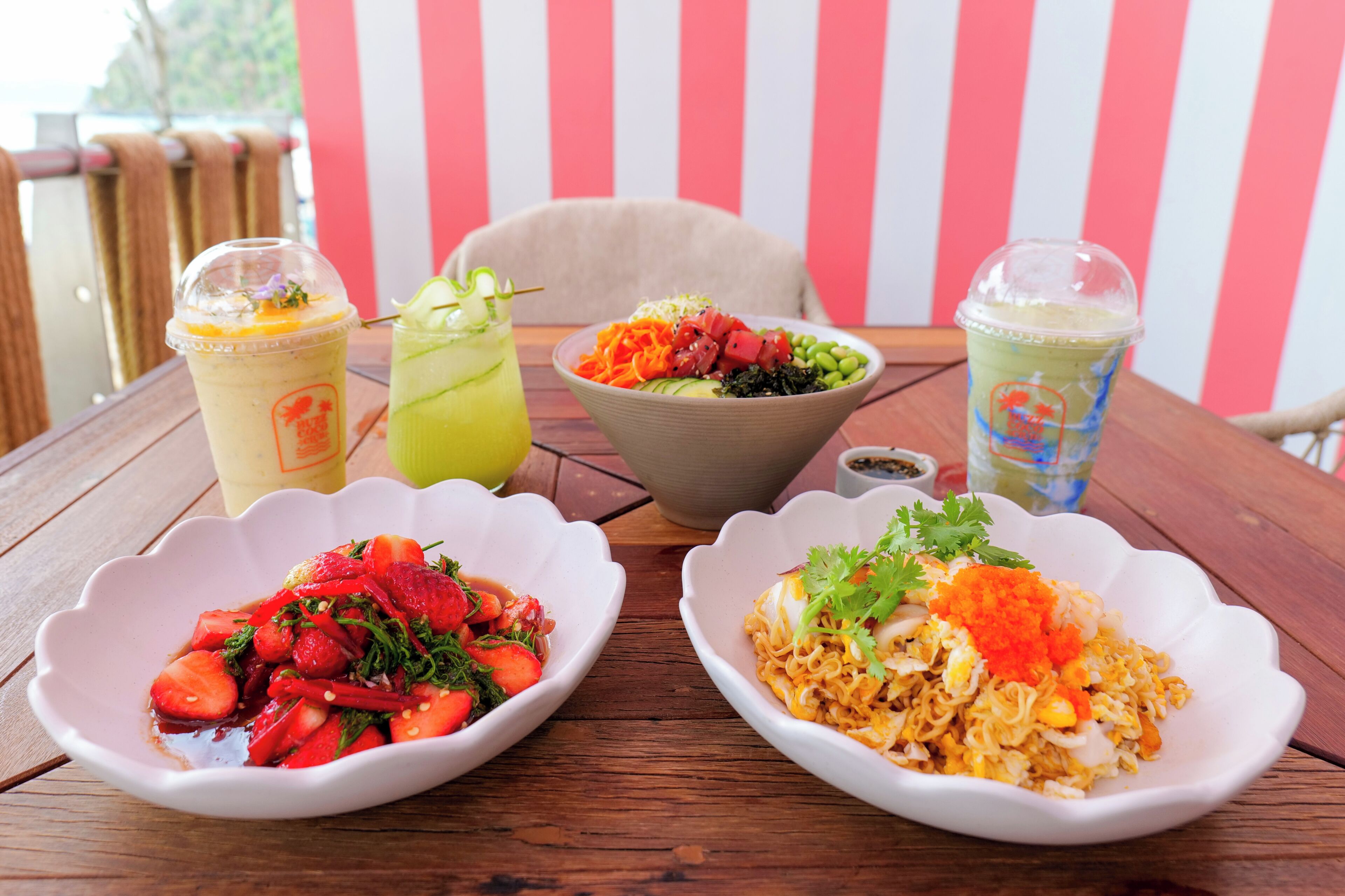 A table with three bowls of food and three drinks.