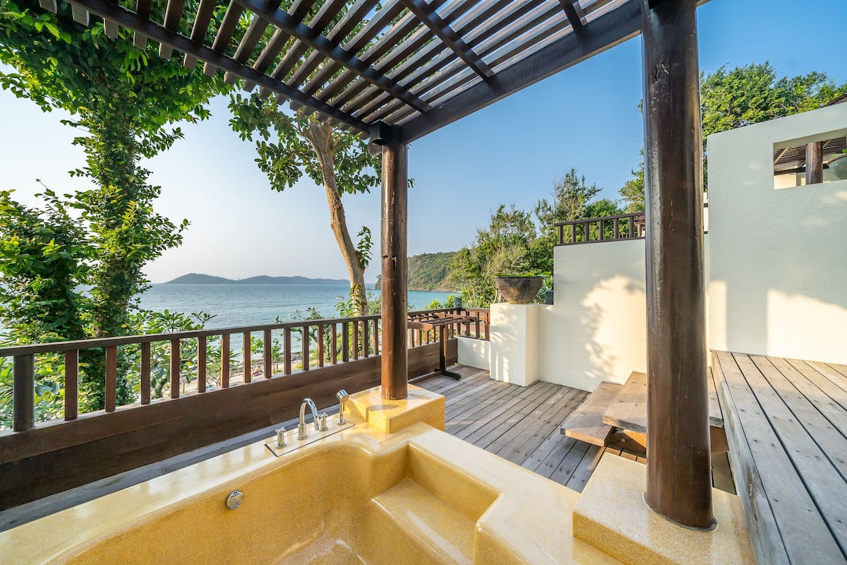 A wooden deck with a built-in sink and a view of the sea.