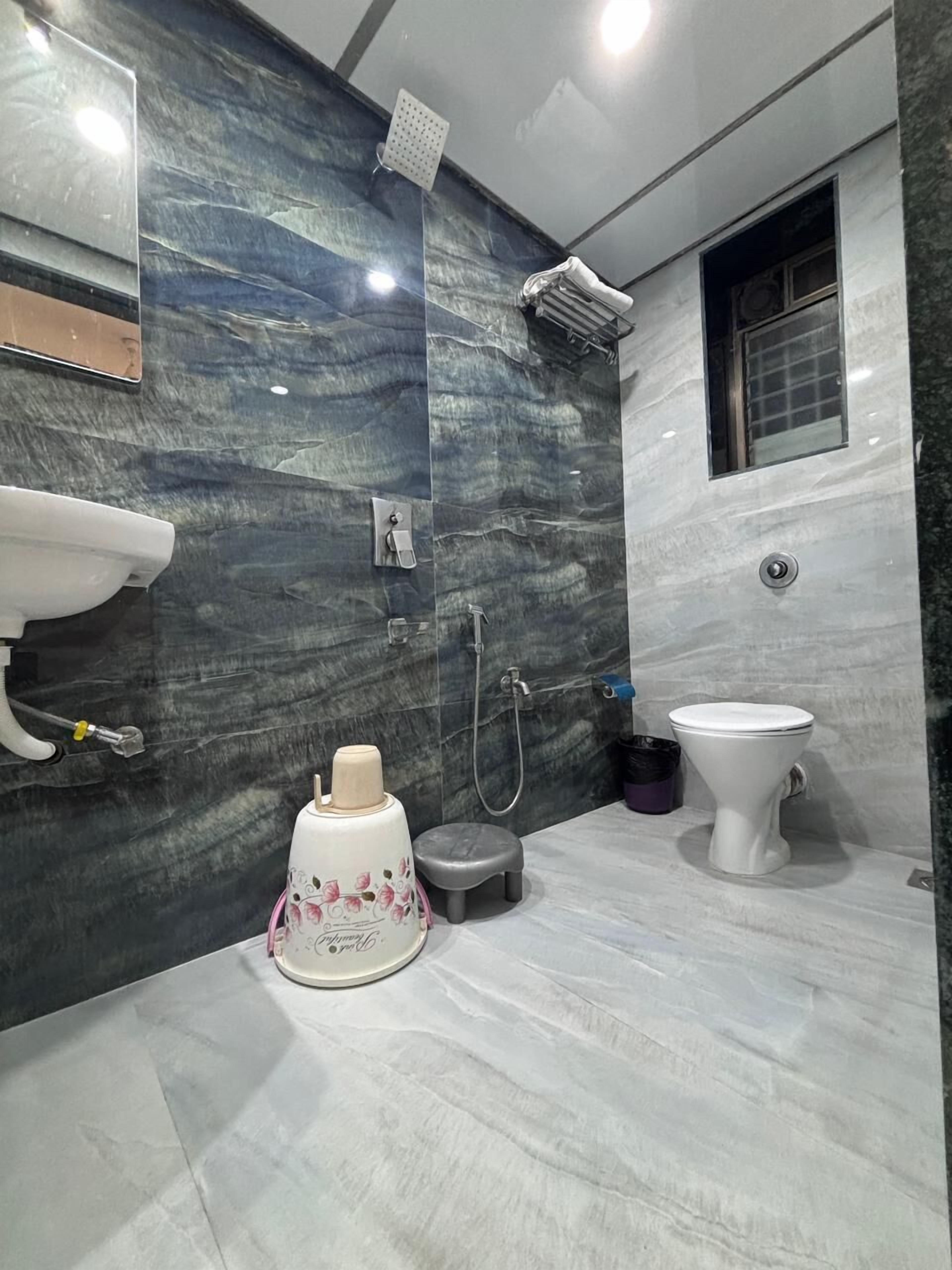 Une salle de bain moderne avec un mur en marbre, un lavabo, des toilettes et une douche.