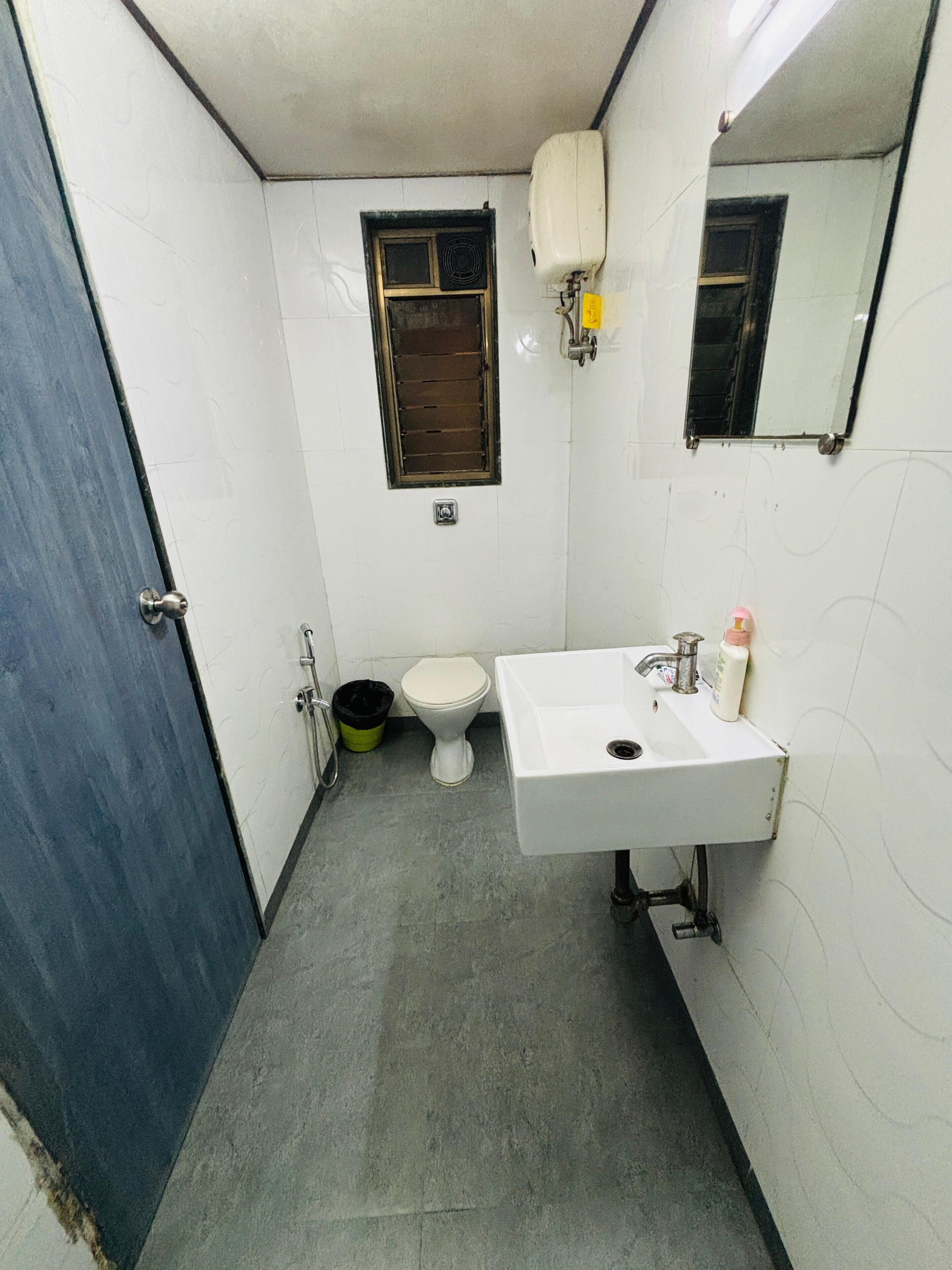 Un baño pequeño y funcional con inodoro, lavamanos y ventana con calefacción.
