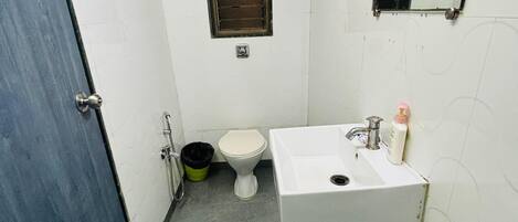 Un baño pequeño y funcional con inodoro, lavamanos y ventana con calefacción.