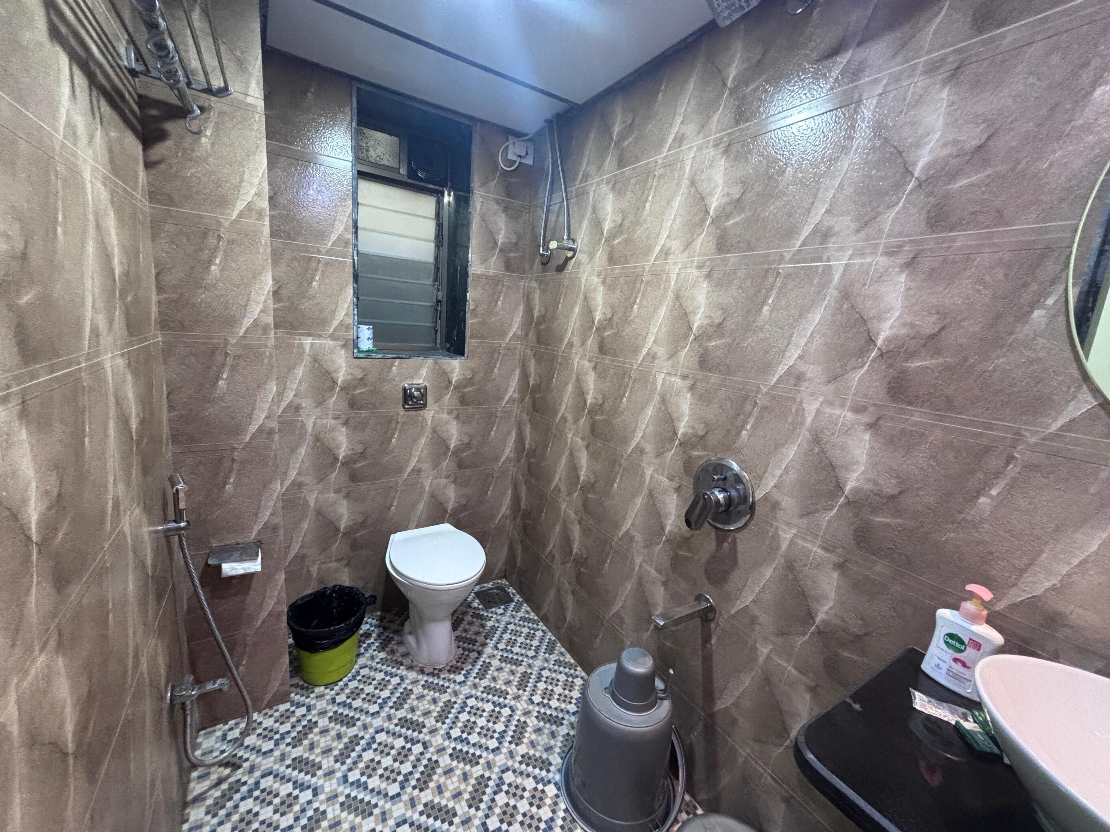 A bathroom with a toilet, a shower, a sink, and a small window.