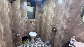 A bathroom with a toilet, a shower, a sink, and a small window.