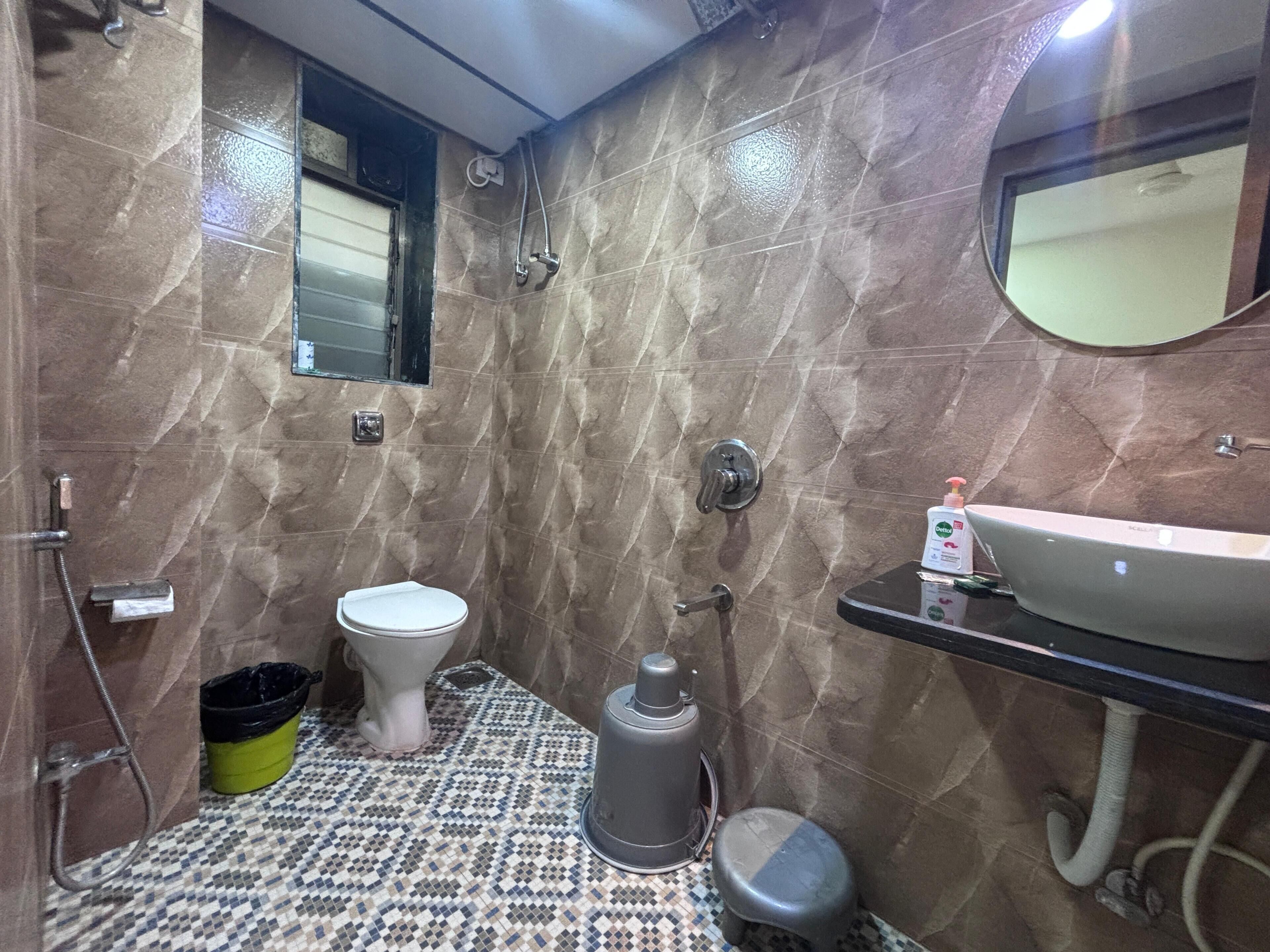 Une salle de bain équipée de toilettes, d’un bidet, d’un lavabo et d’une poubelle.