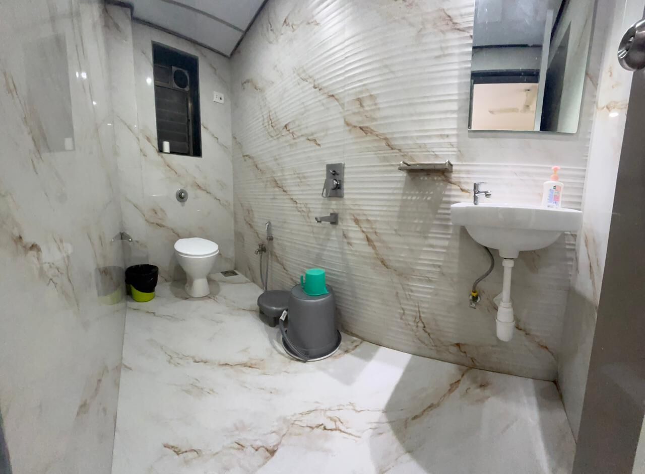 Een badkamer met toilet, wastafel en een marmeren wand.