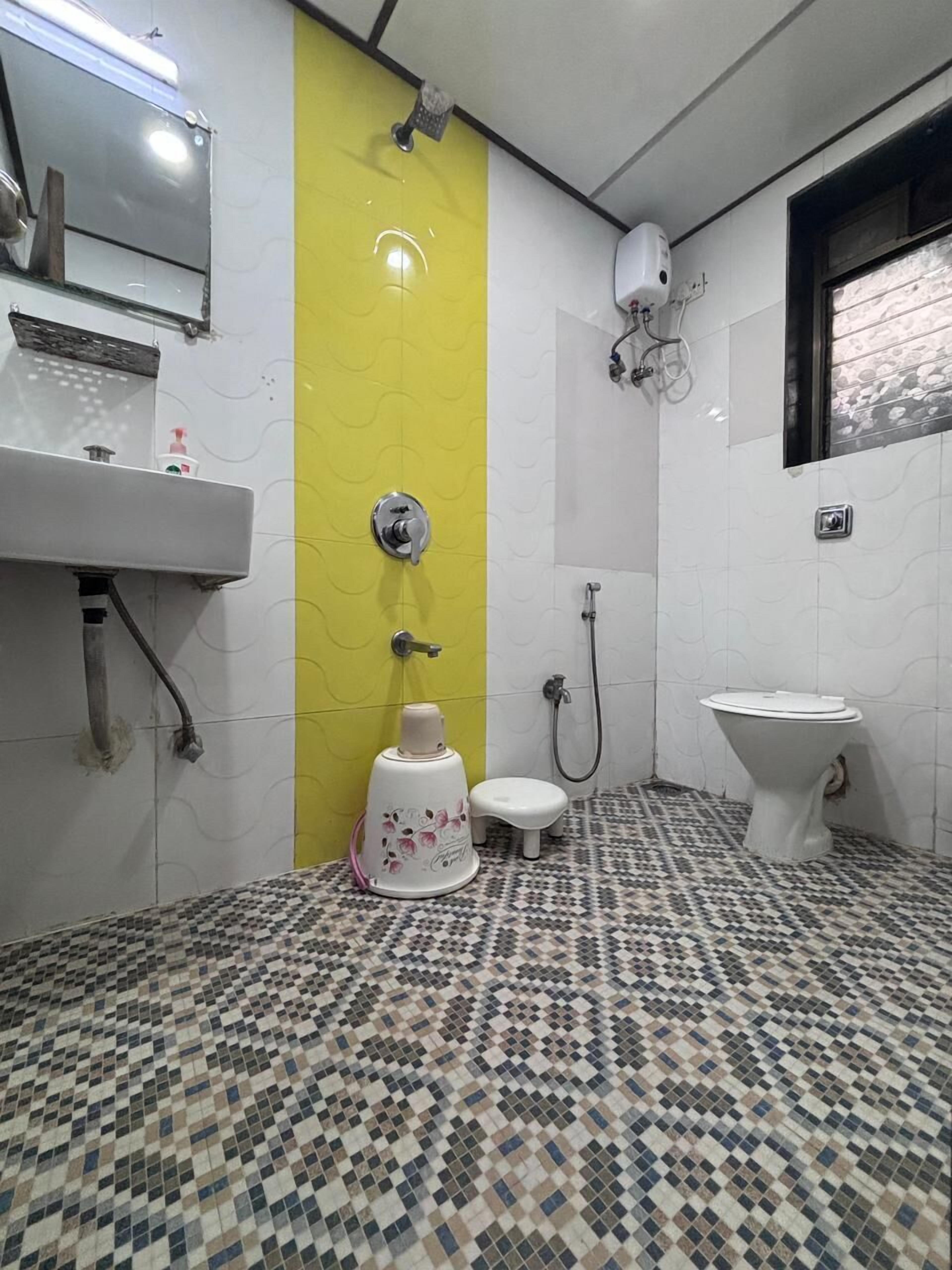 A bathroom with a tiled floor, a toilet, a sink, and a shower.