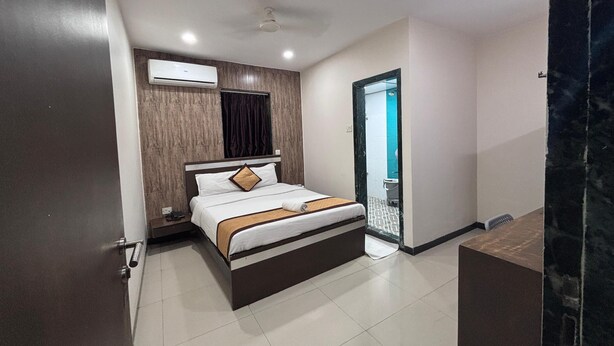Ein modernes Hotelzimmer mit einem Bett, einem Deckenventilator, einer Klimaanlage, einem Badezimmer mit Toilette und Waschbecken sowie einem Boden, der an Marmor erinnert.