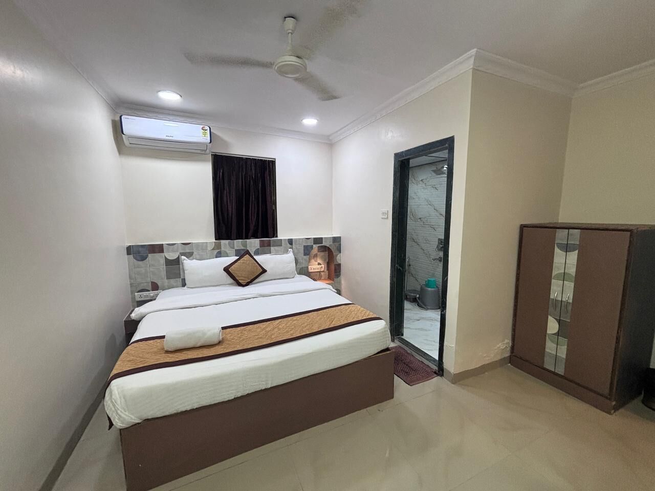 A bedroom with a bed, a wardrobe, a ceiling fan, and an air conditioning unit.