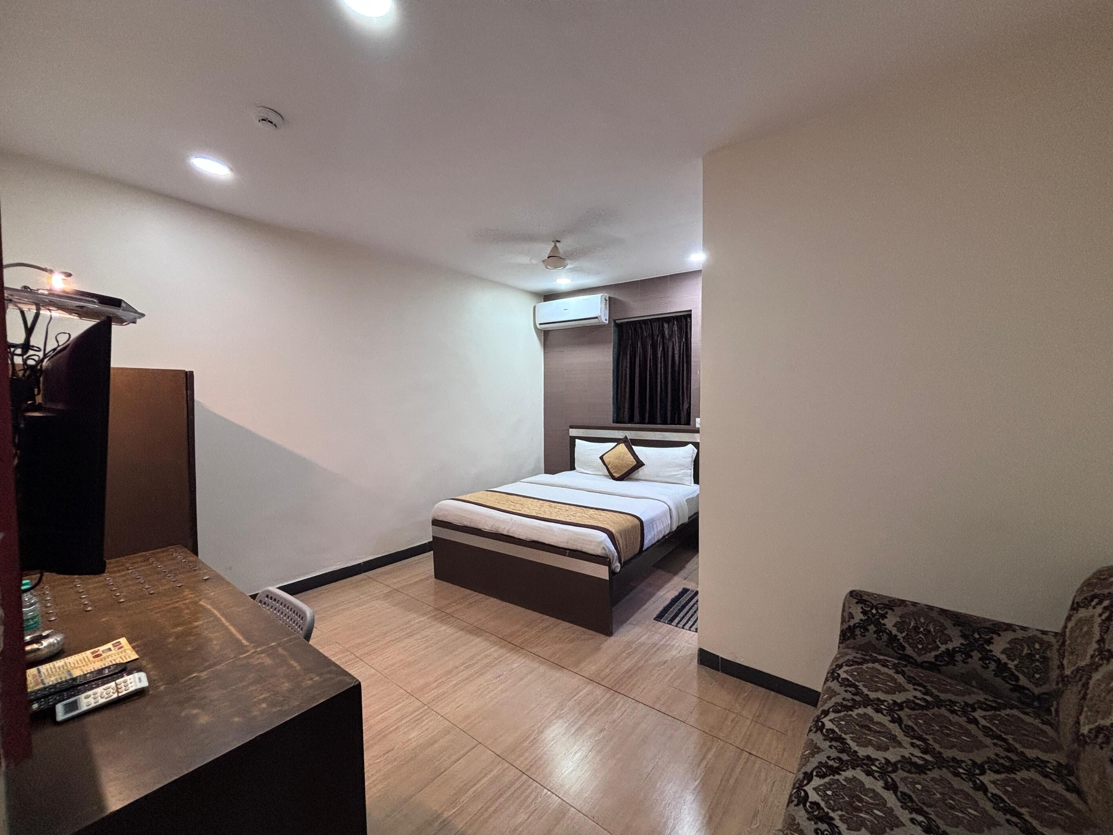 A hotel room with a bed, a desk, a chair, and a sofa.