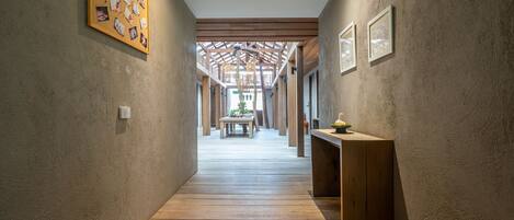 A corridor with wooden flooring, a wooden bench, and framed pictures on the walls.