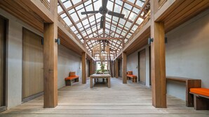 A corridor with wooden flooring, benches, and a ceiling fan.
