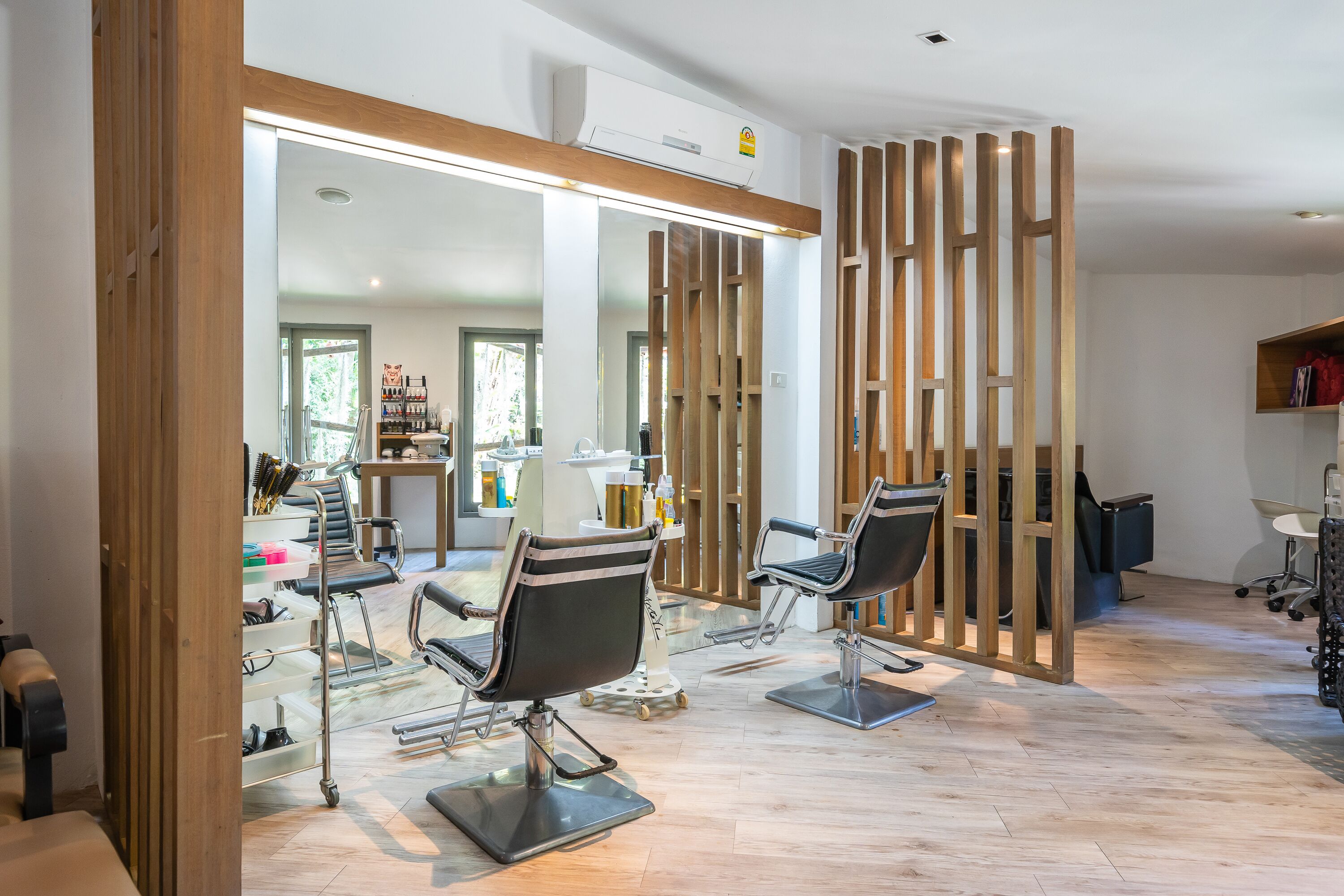 Un salon moderne avec deux fauteuils noirs, un grand miroir et des cloisons en bois.