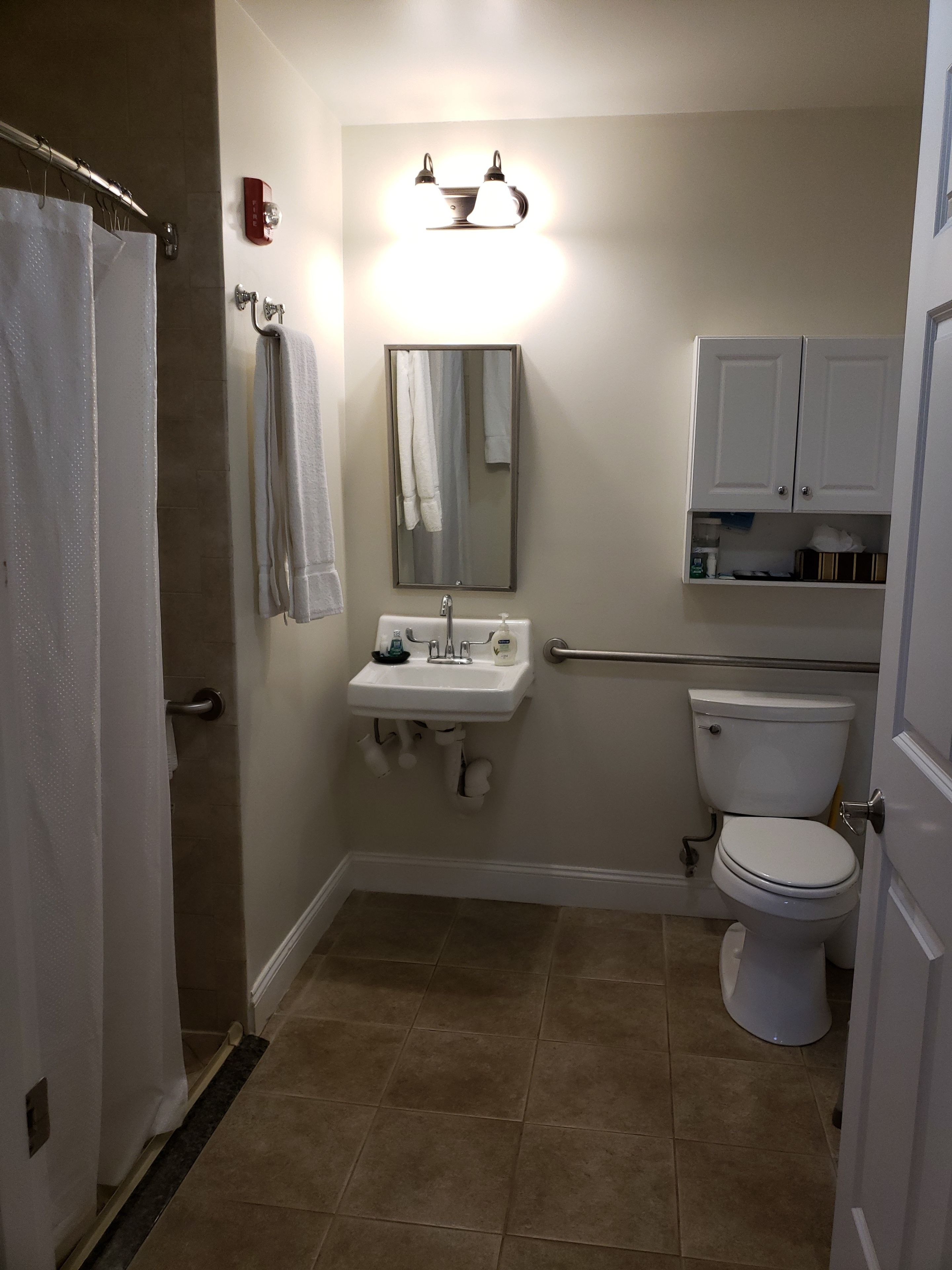 A bathroom with a toilet, sink, mirror, towel rack, and a shower curtain.