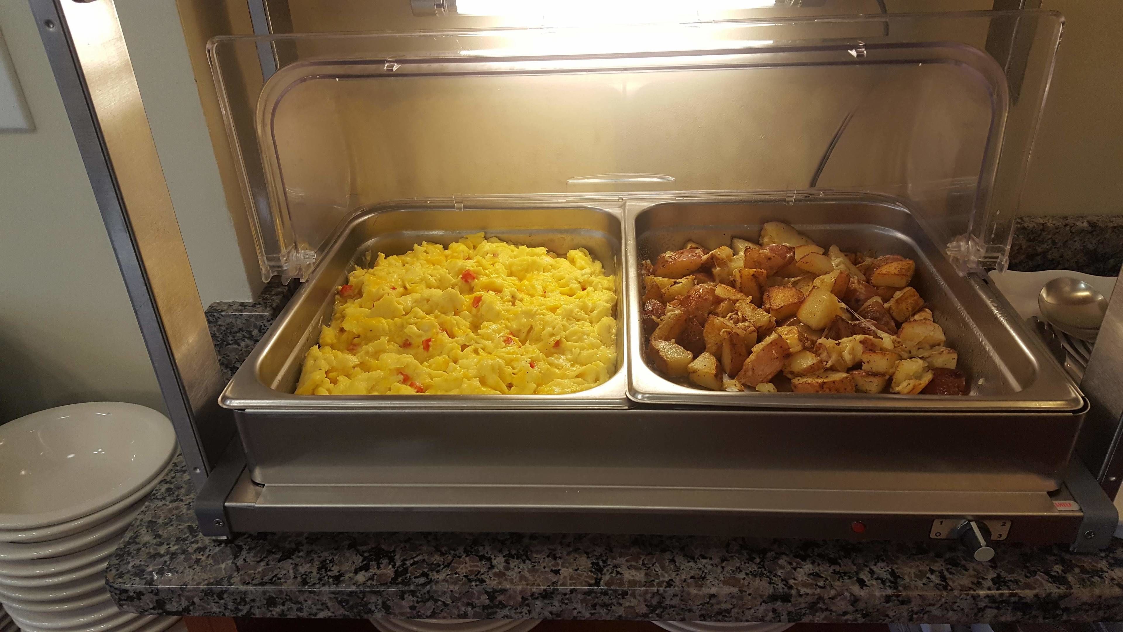 Un bufé con huevos revueltos y patatas asadas.