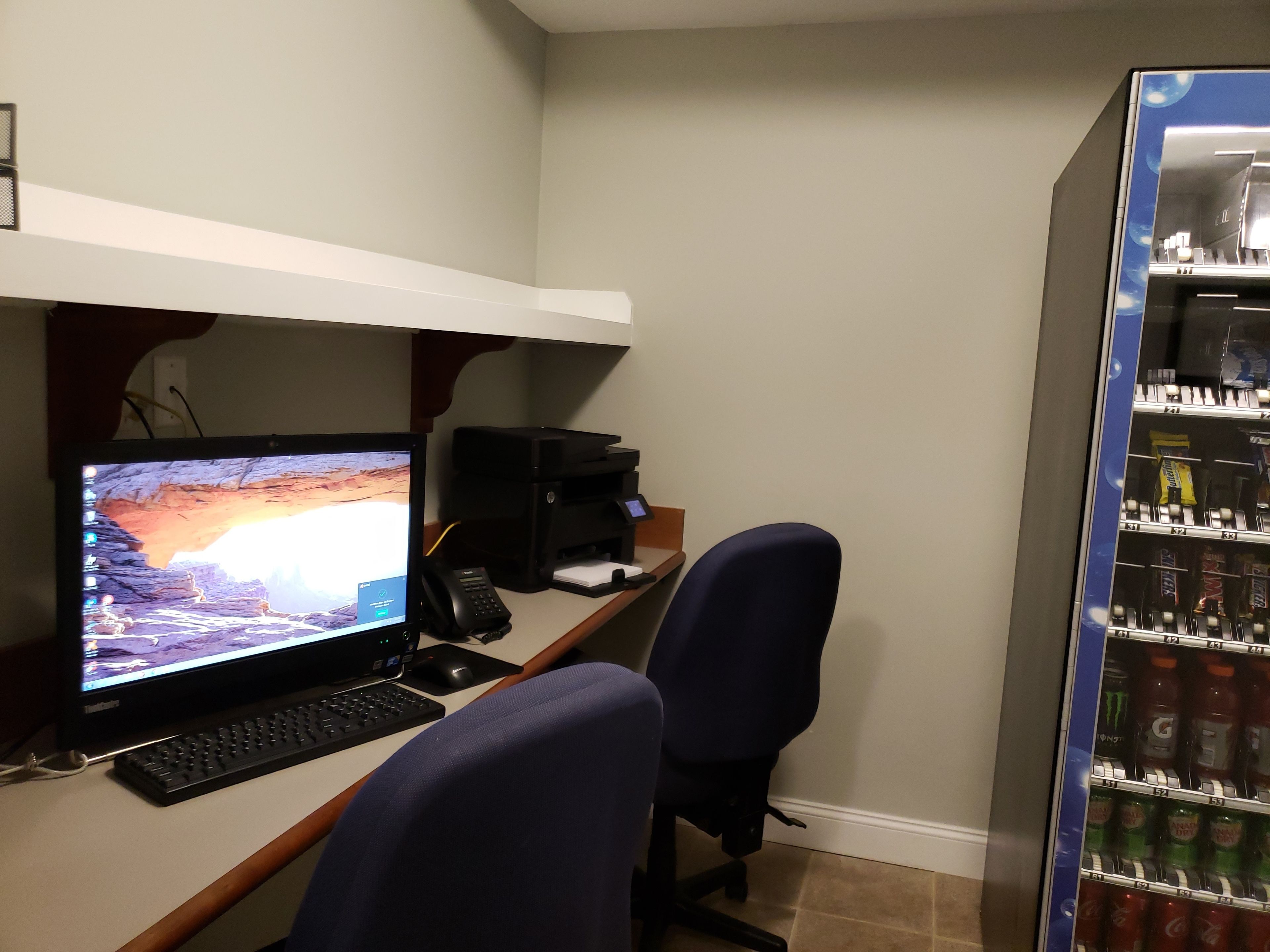 A home office with a desktop computer, printer, and two chairs.