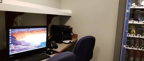 A home office with a desktop computer, printer, and two chairs.