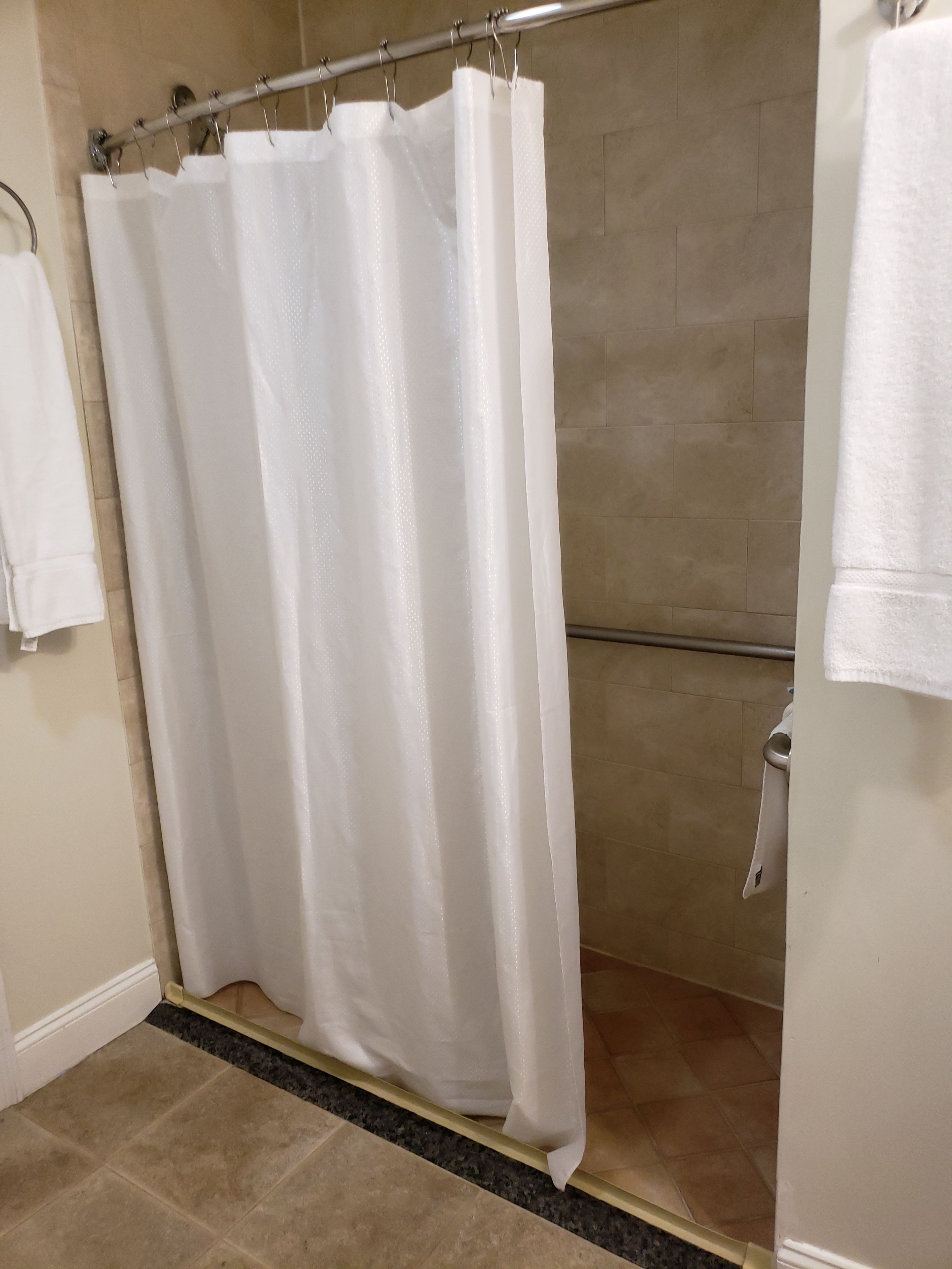 A bathroom with a shower curtain, tiled walls, and a towel rack.