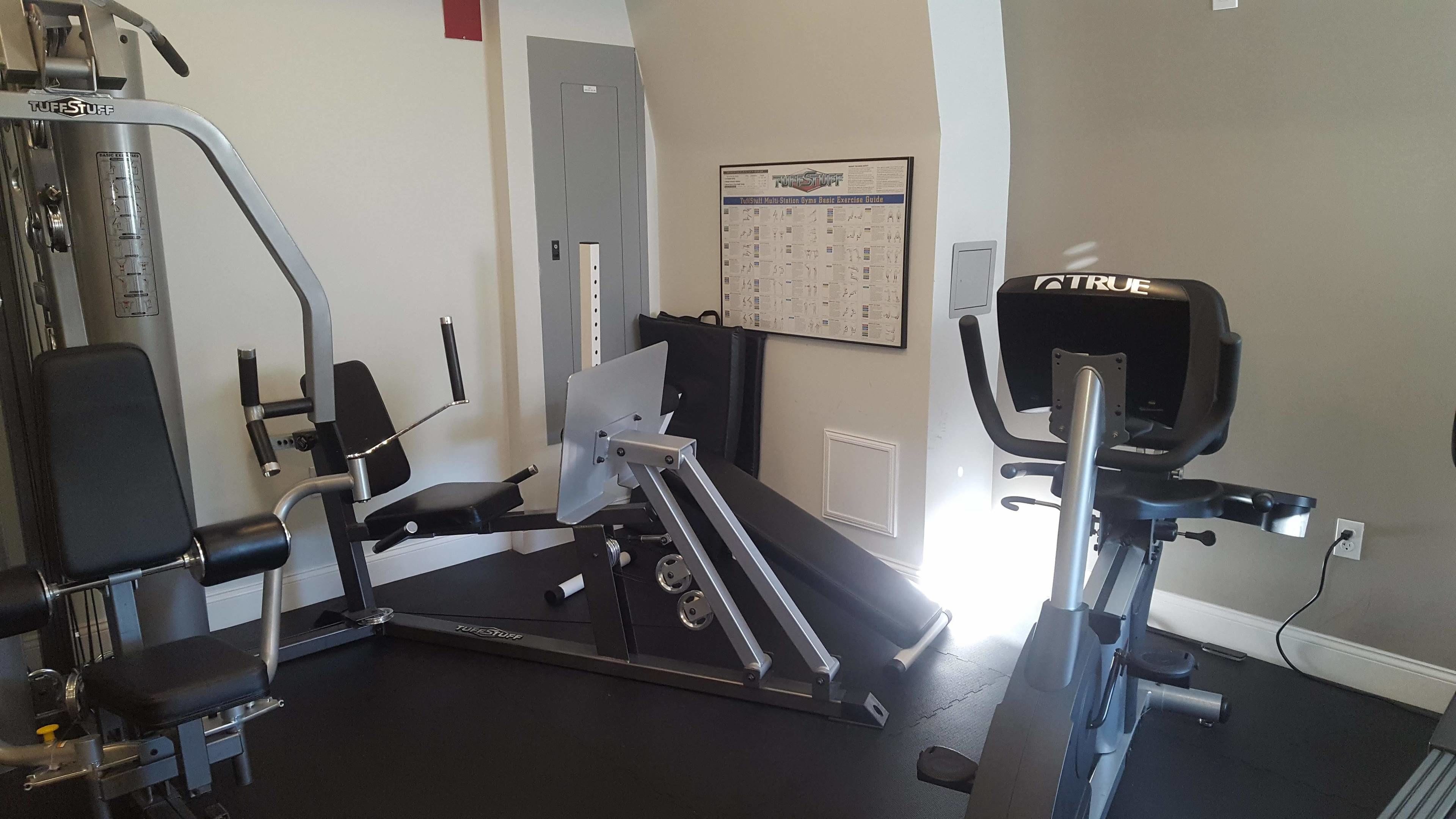A gym with TuffStuff equipment, a wall calendar, and a TRU desk.