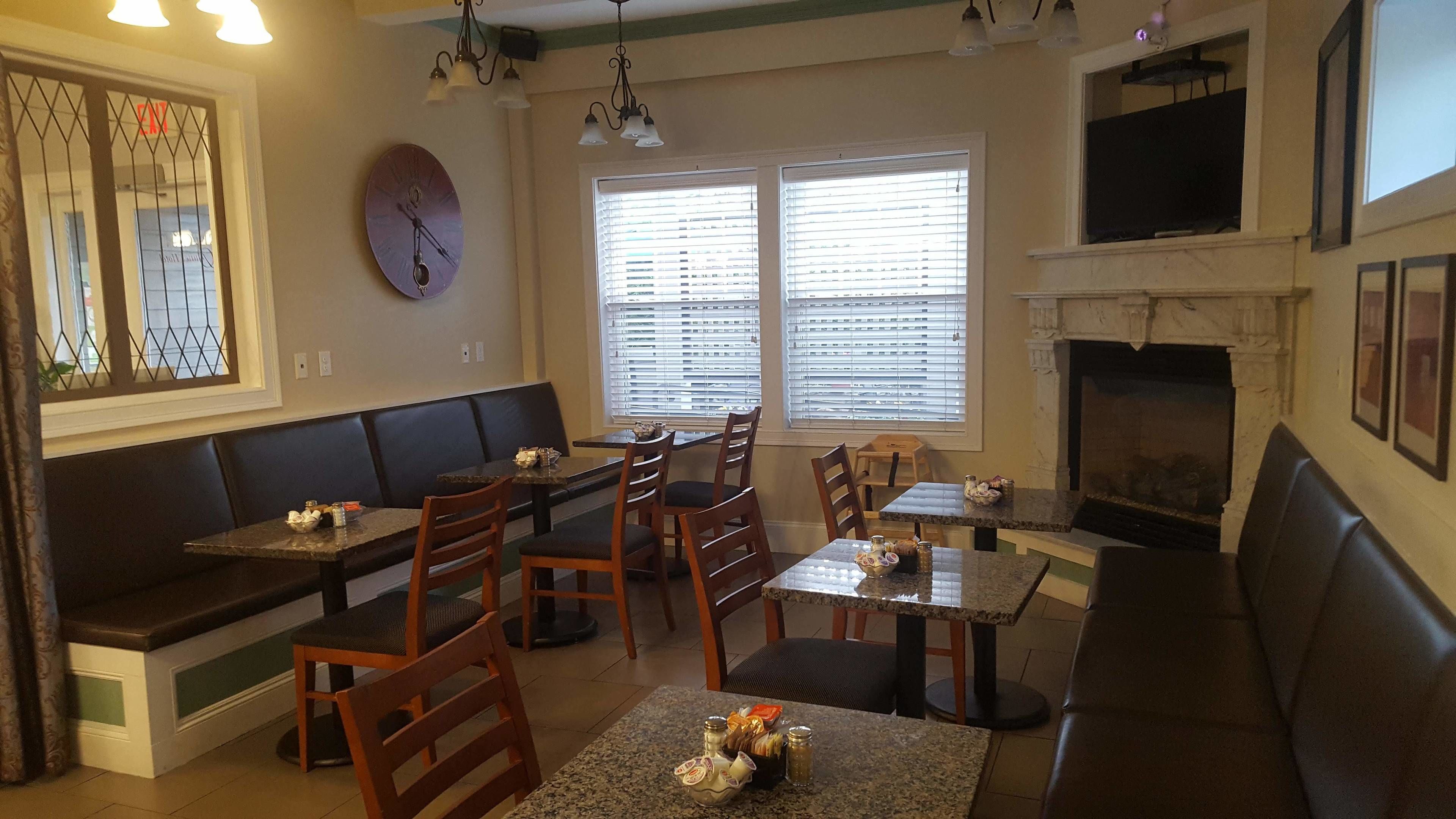 A dining area with a fireplace, a clock, and a window with blinds.