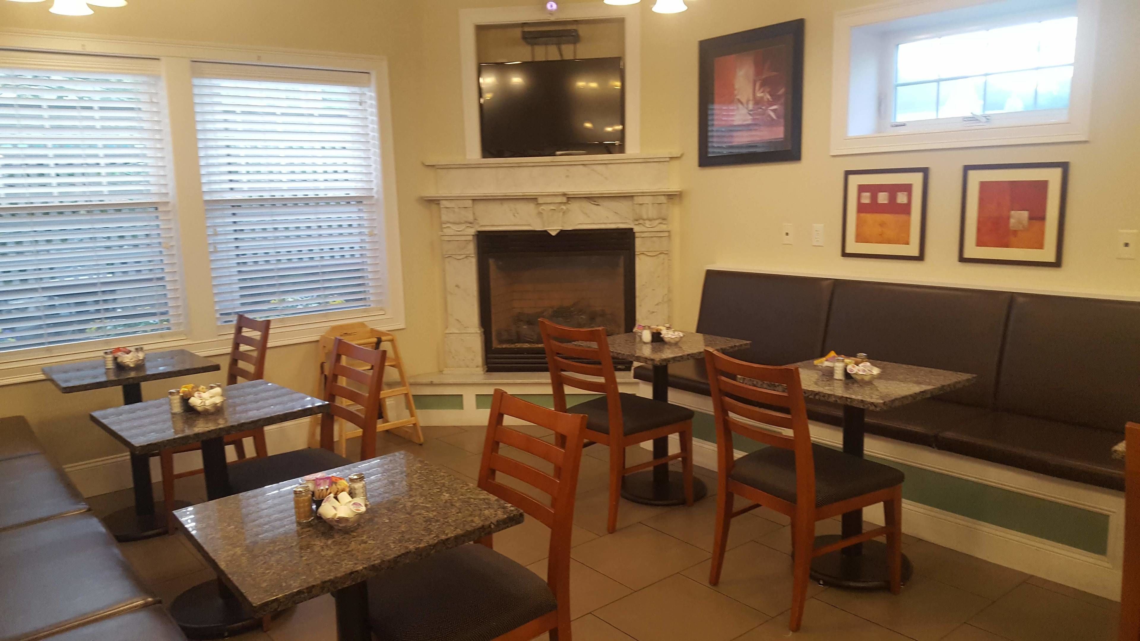 L’intérieur d’un restaurant, avec des tables et des chaises, une cheminée et des œuvres d’art encadrées accrochées aux murs.