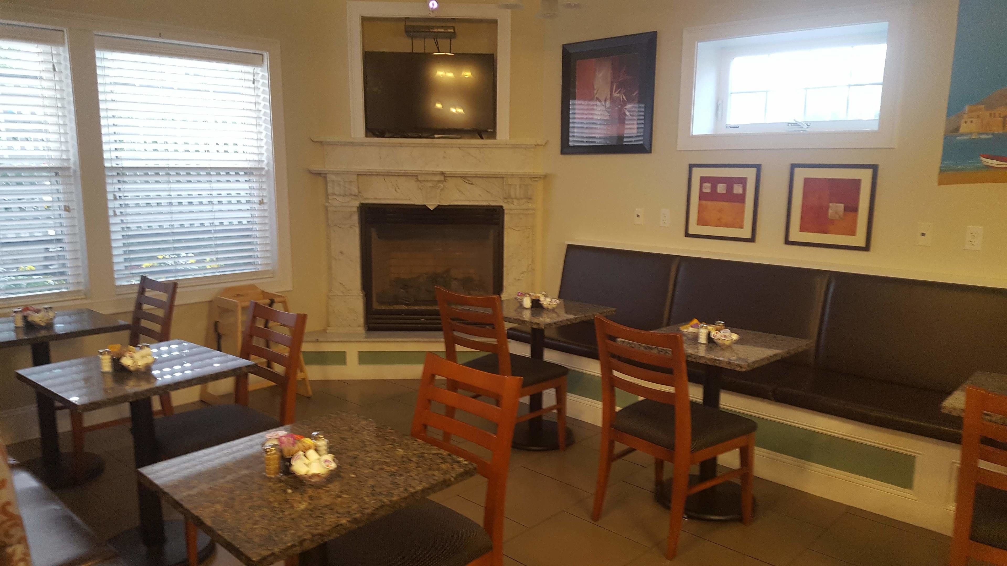 A restaurant with wooden tables and chairs, a fireplace, and framed artwork on the walls.