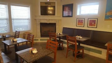 A restaurant with wooden tables and chairs, a fireplace, and framed artwork on the walls.