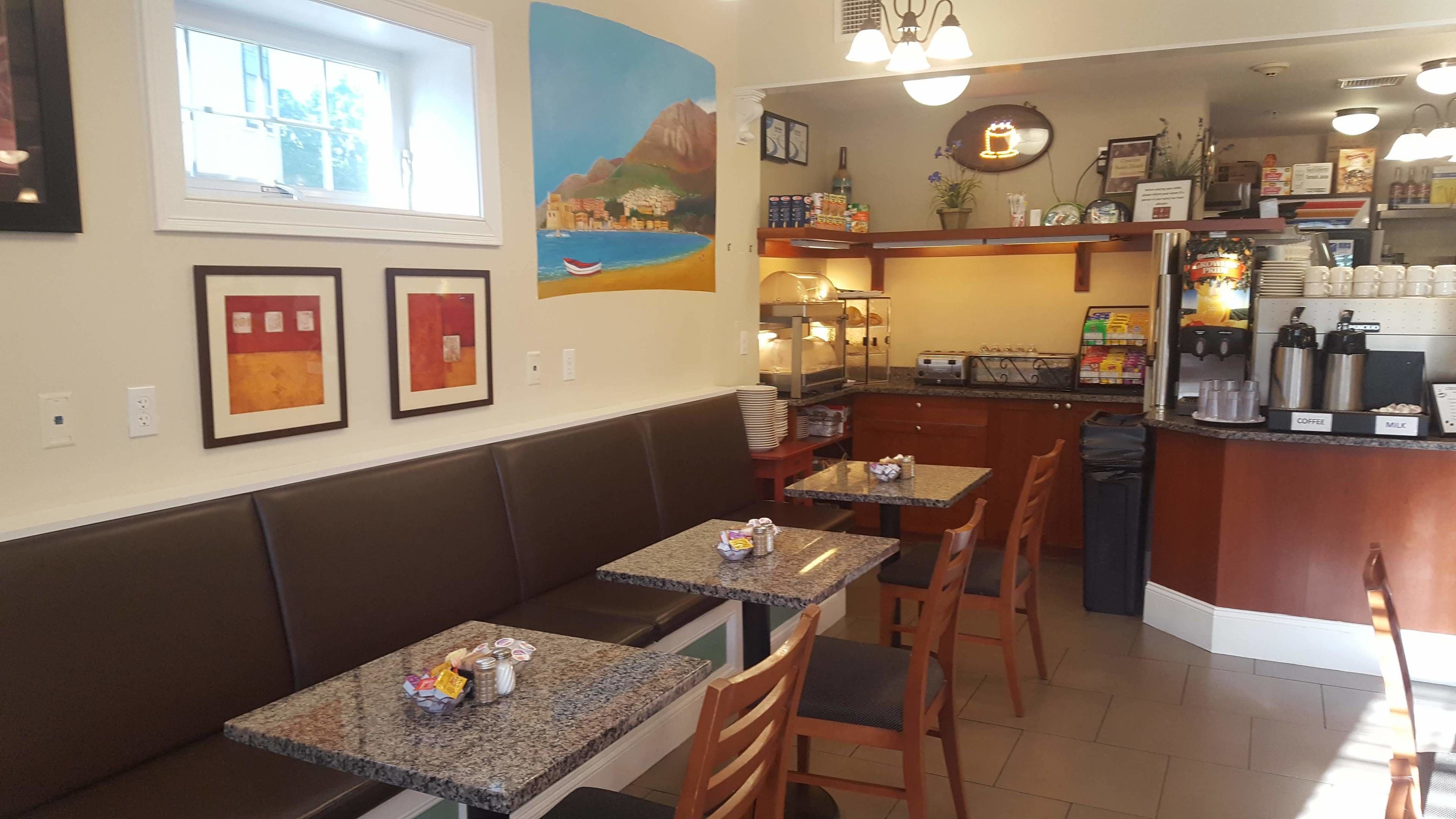Un restaurante con mesas, cabinas, una zona de cocina y obras de arte en las paredes.