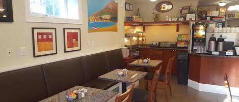 A restaurant with booths and tables, a kitchen area, and artwork on the walls.