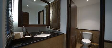 Un baño con lavamanos doble, inodoro y espejo.