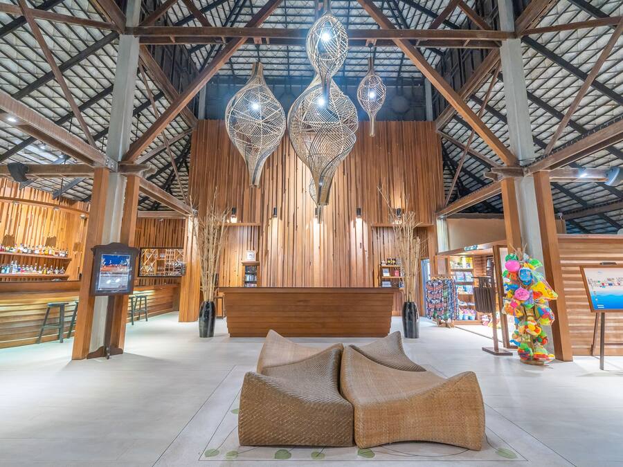 A spacious lobby with a wooden reception desk, hanging decorative lights, and a colorful art installation.